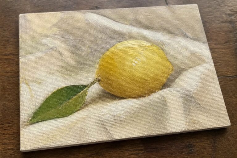 Yellow lemon with green leaf on white paper over wooden surface in oil painting