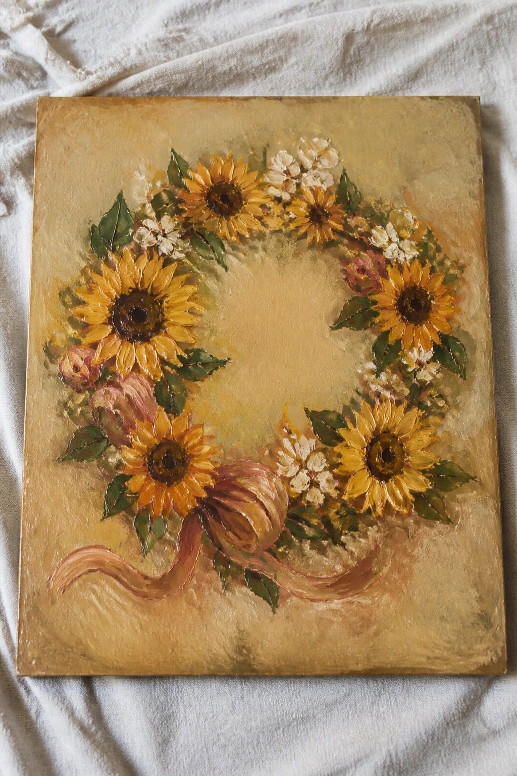 Painted sunflower wreath with white flowers, pink roses, and brown ribbon on gold background