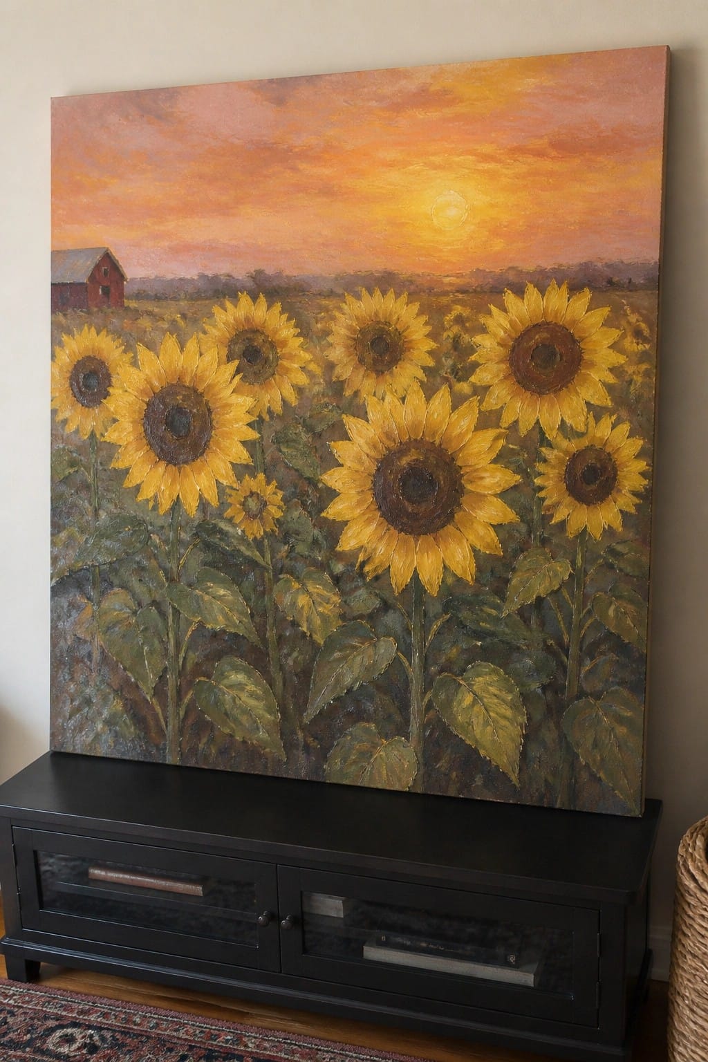 Large sunflower painting at sunset with red barn above black media console.