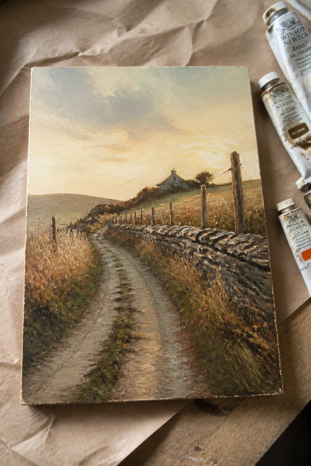 Landscape painting of rural path by stone wall with Winsor Newton oil paint tubes.