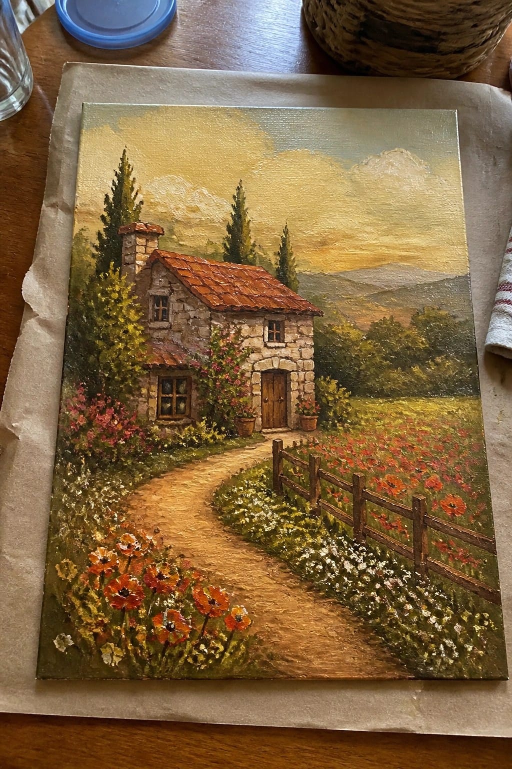 Stone cottage with red roof along path by wooden fence and red poppy field
