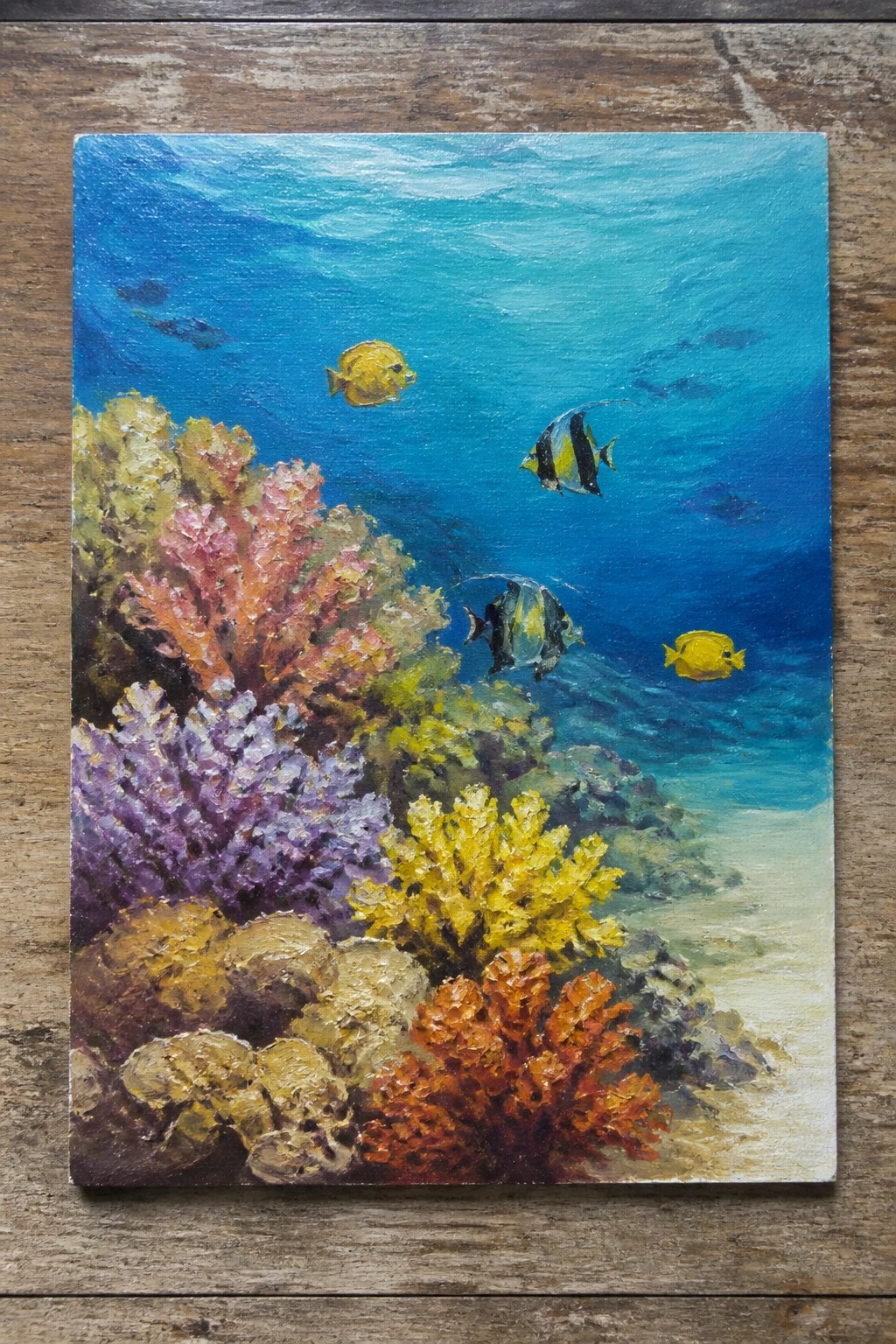Vibrant painting of tropical fish swimming among colorful corals in blue ocean.