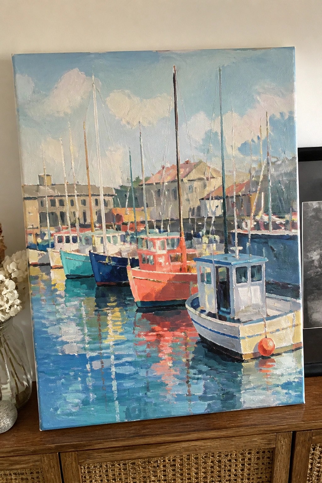Impressionistic painting of colorful boats docked in a reflective harbor with buildings