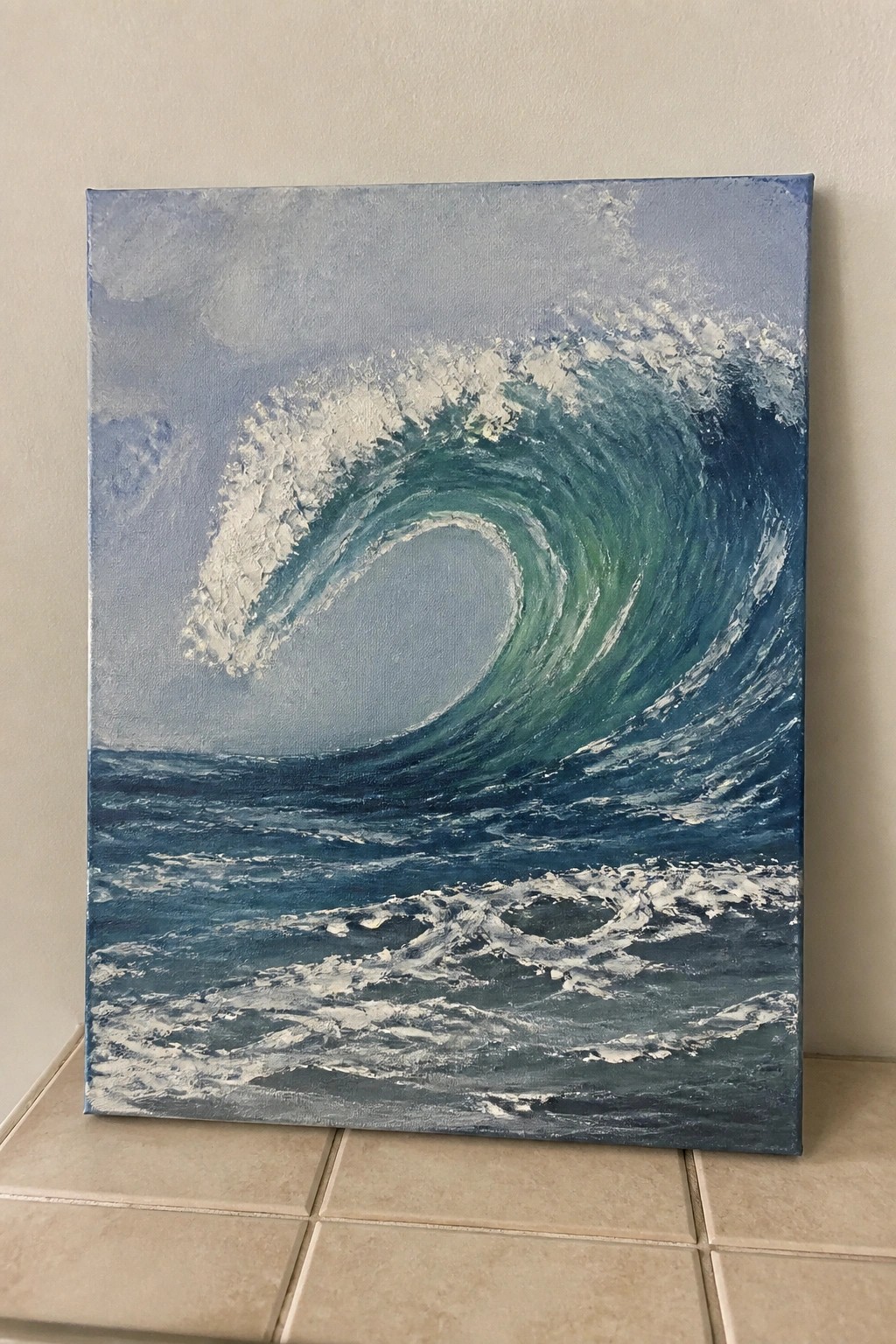 Canvas painting of a curling blue-green ocean wave with white foam on tiled floor.
