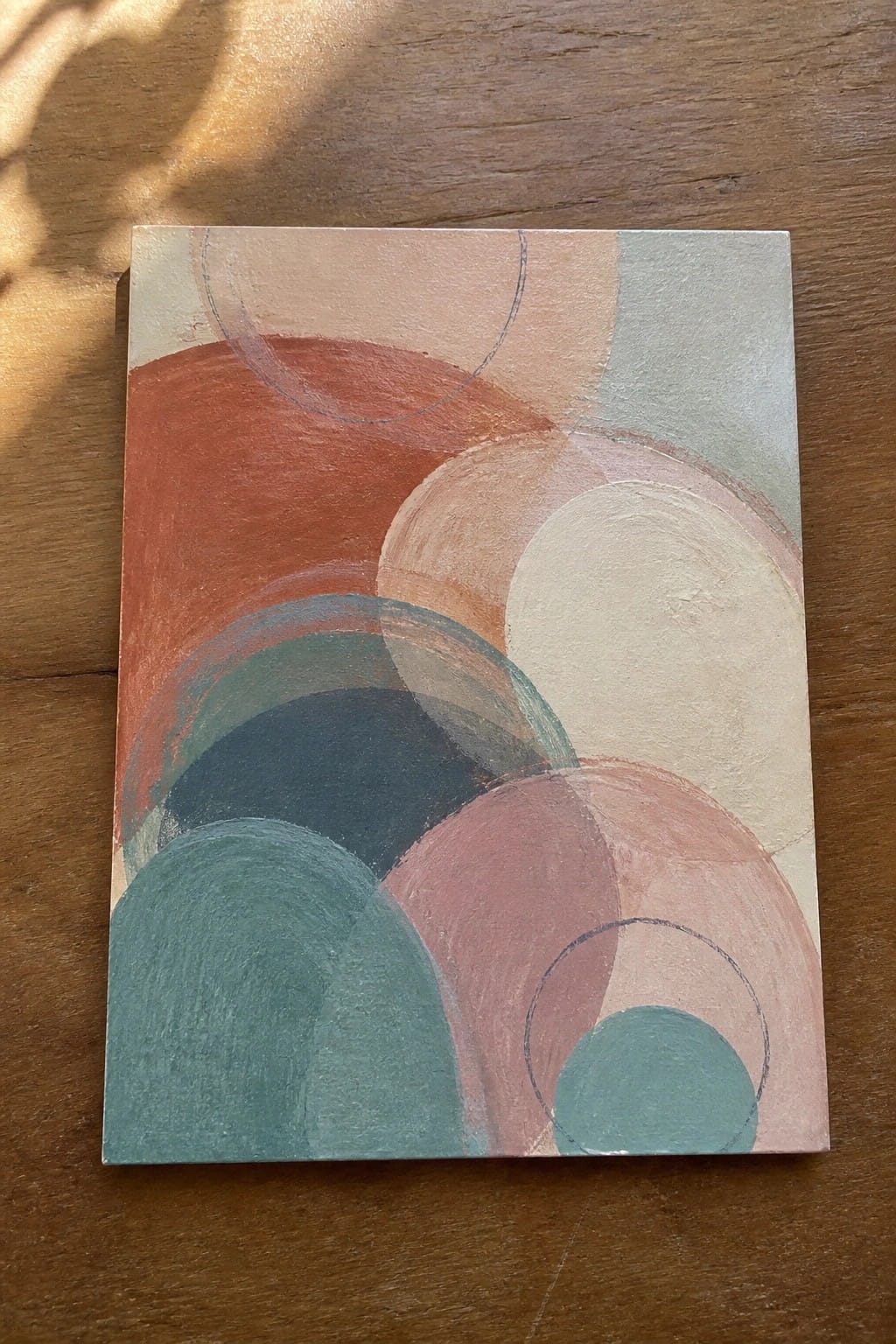 Abstract painting of overlapping circles in terracotta, teal, pink, and beige tones.