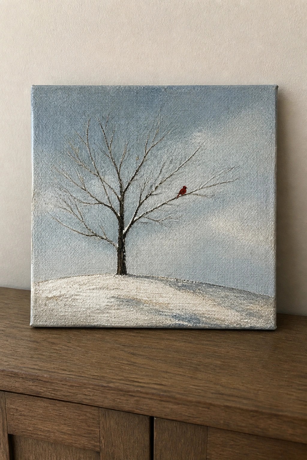 Square canvas shows bare tree with red bird on snowy ground under blue-gray sky.