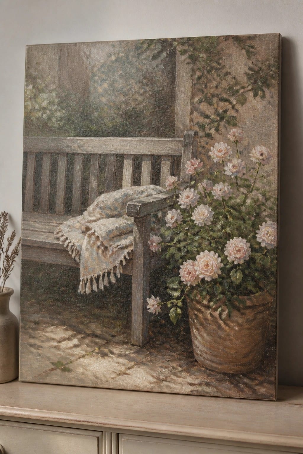 Painting of wooden bench with blanket beside pot of pink roses on stone.