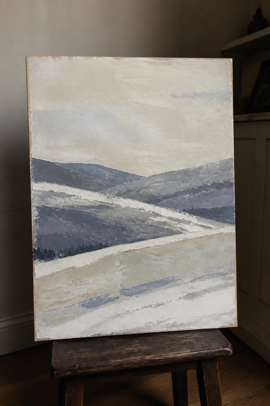 Abstract landscape painting with blue-gray hills on wooden stool