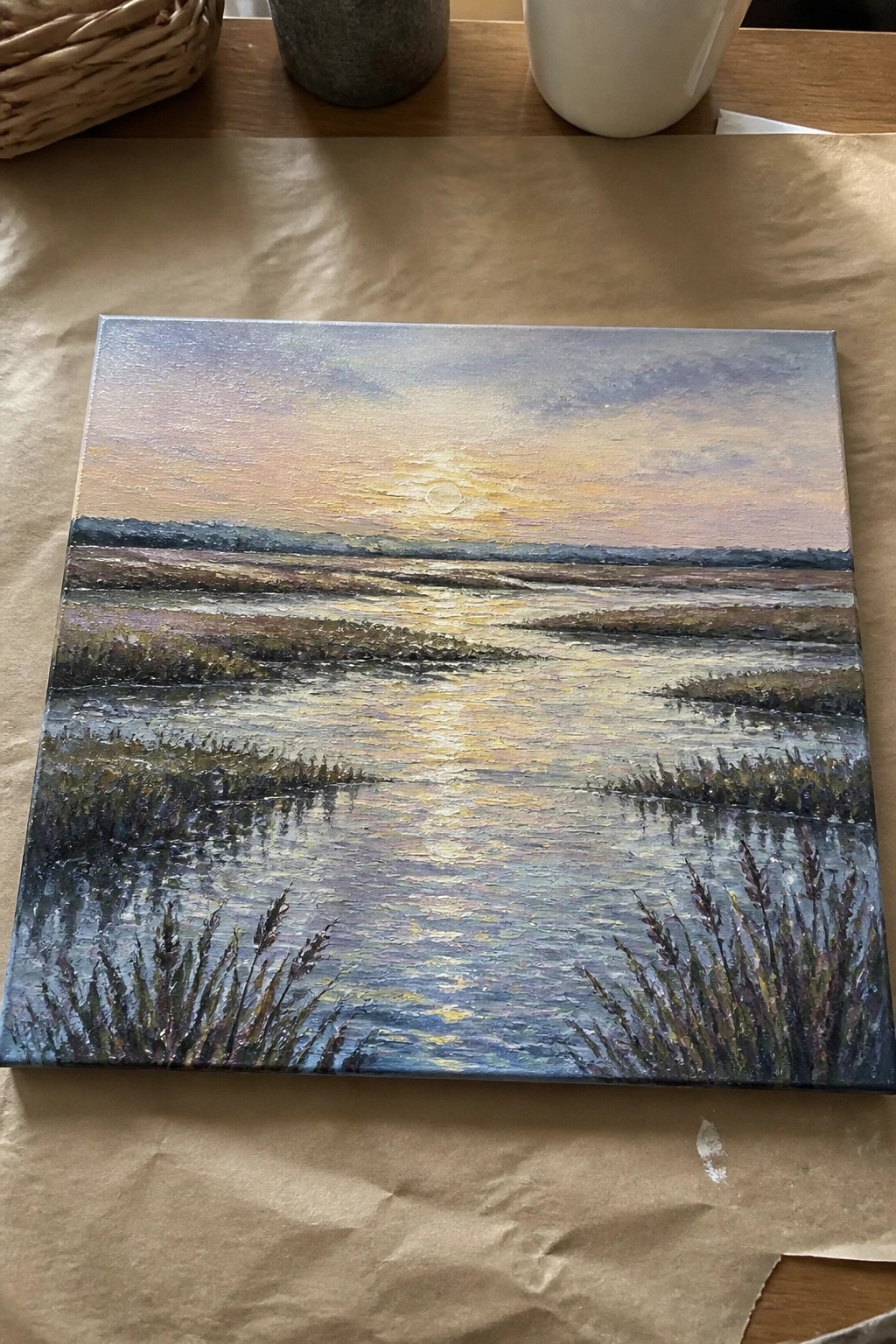 Painting of sunset over calm marsh with golden reflections and foreground reeds on canvas.