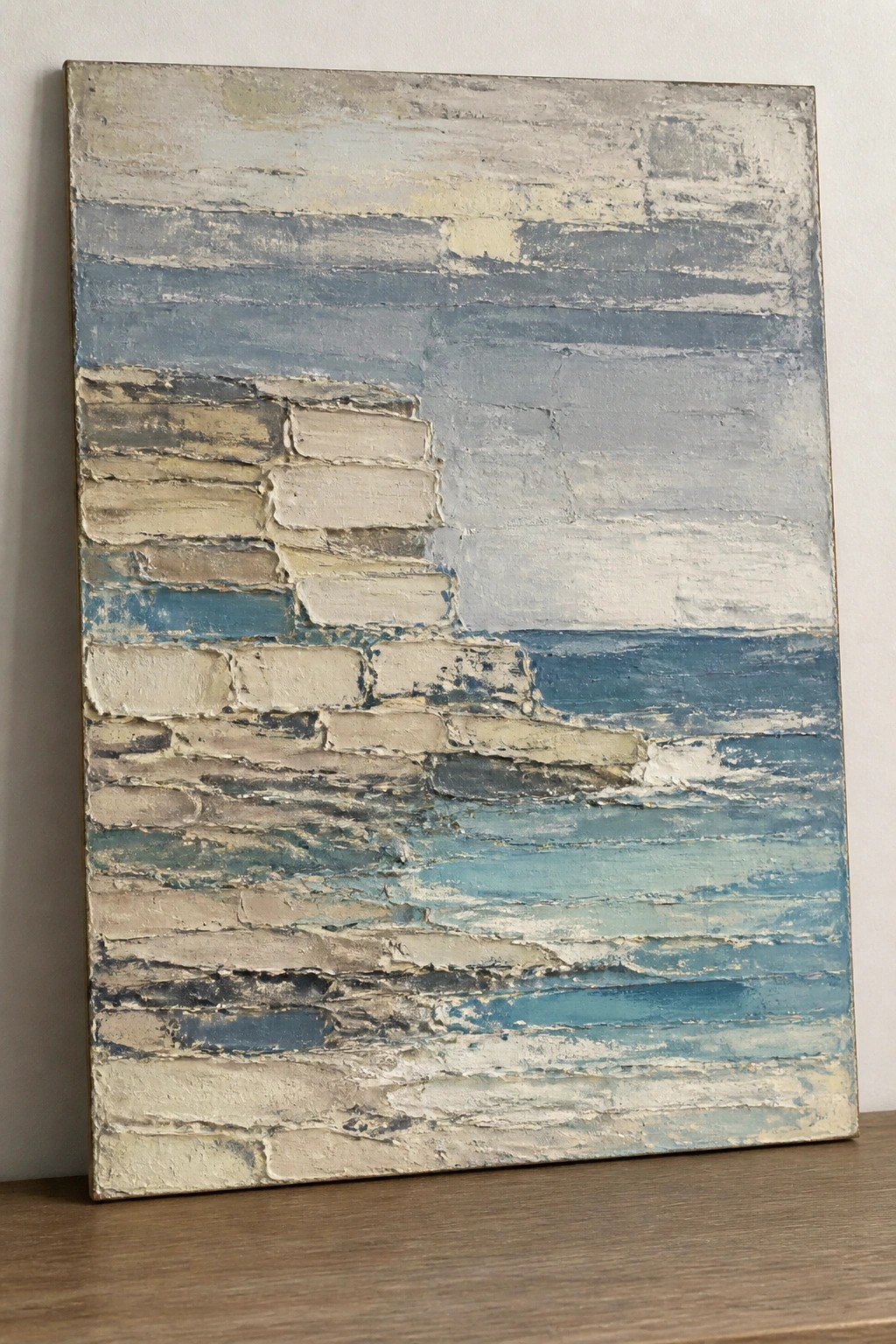 Abstract painting with thick textured layers of blue, gray, beige and white brushstrokes.