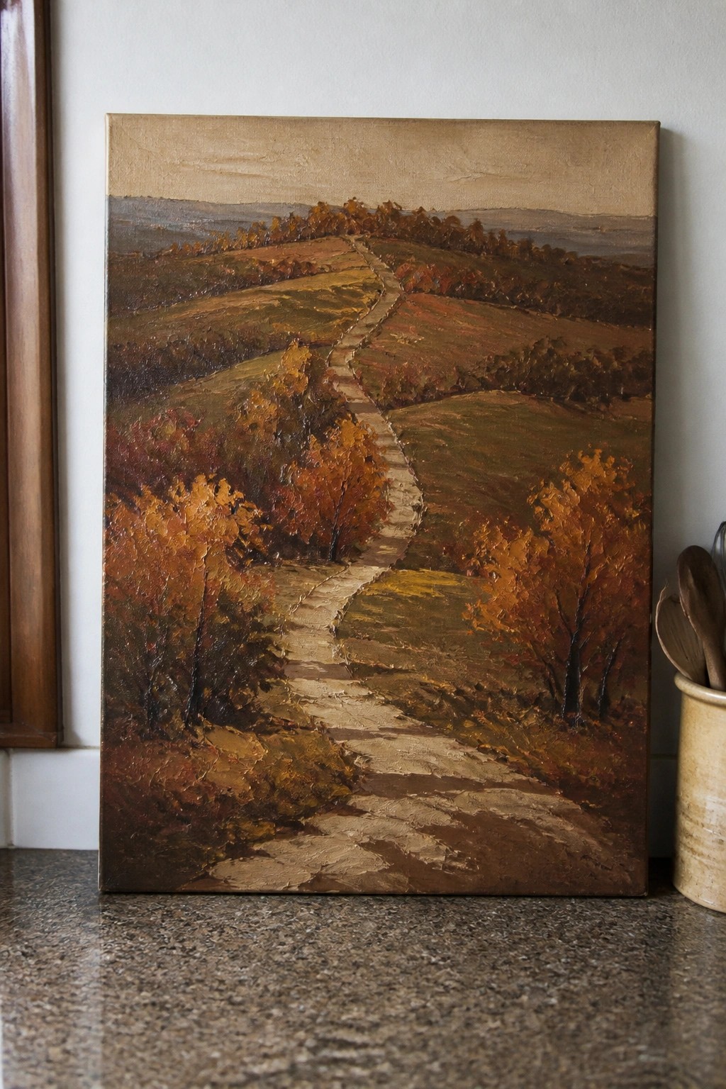 Oil painting of winding path through autumn hills on granite countertop