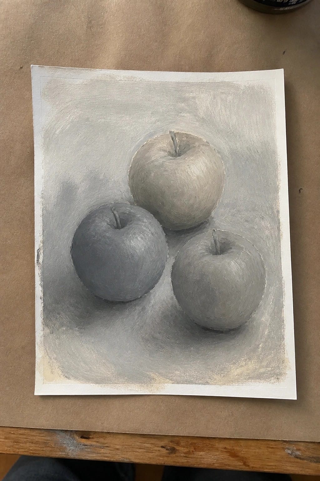 Three gray apples with stems shaded on white paper with soft shadows