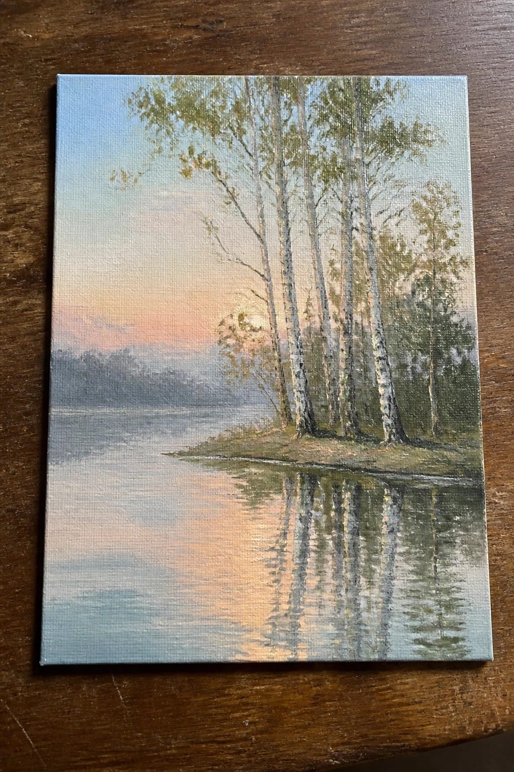 Oil painting of birch trees reflected in a calm lake at sunset.