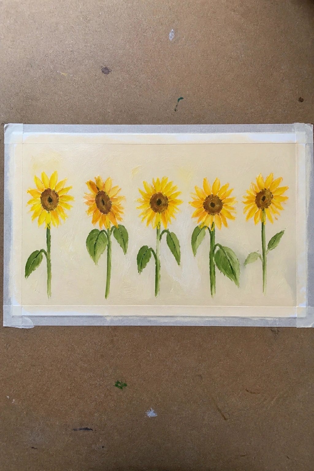 Five yellow sunflowers with green stems on pale yellow painted background