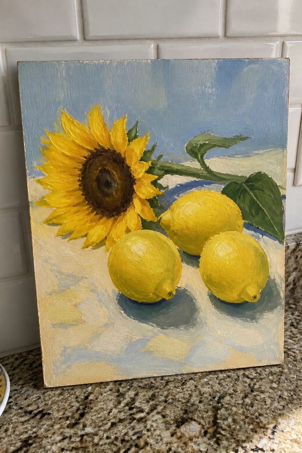 Oil painting of yellow sunflower with three lemons on blue surface.