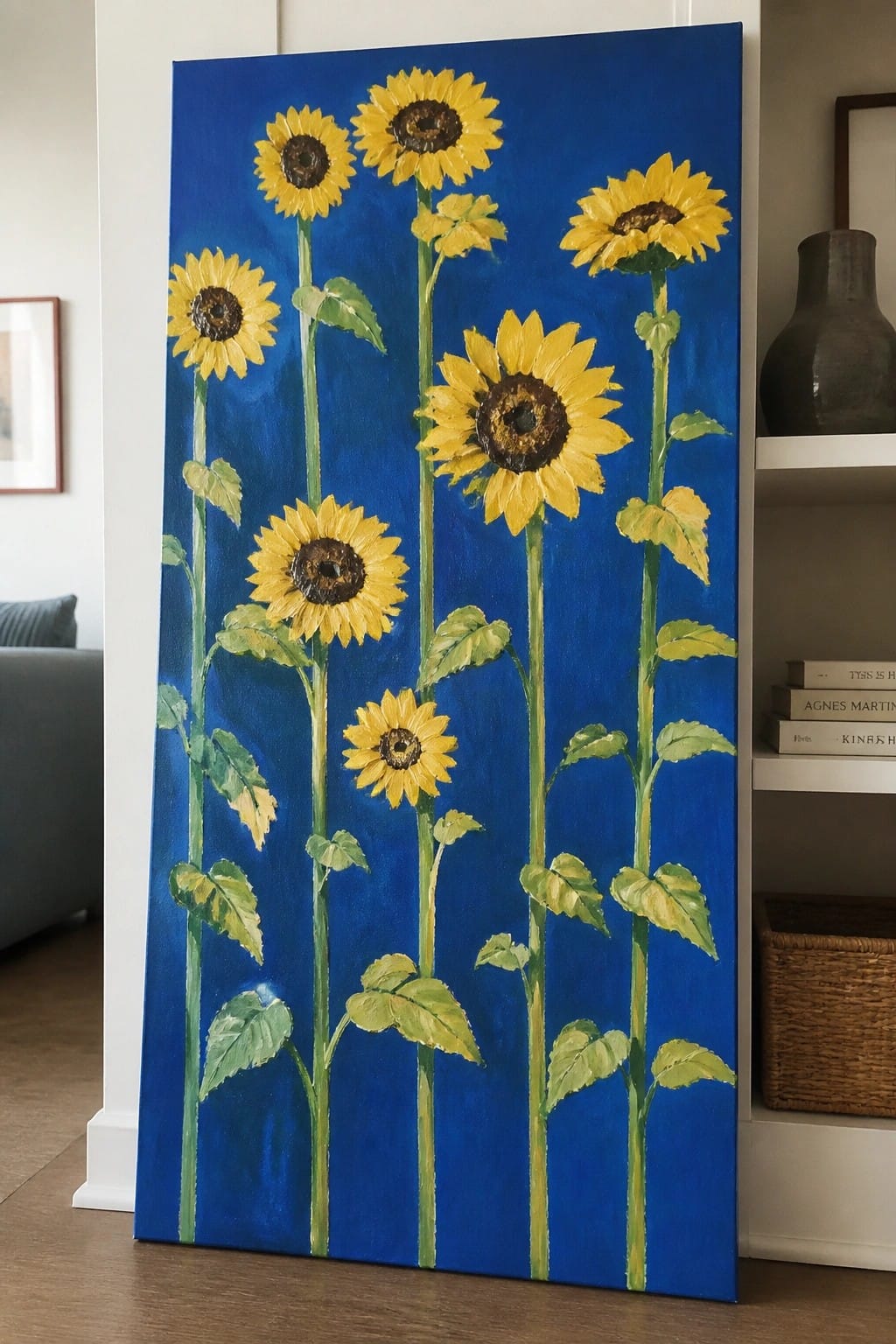 Yellow sunflowers on green stems painted on tall blue canvas in living room.