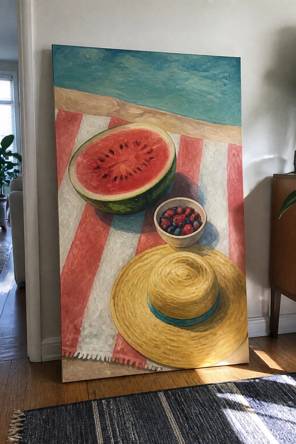 Still life painting of watermelon slice, berry bowl, and straw hat on striped towel