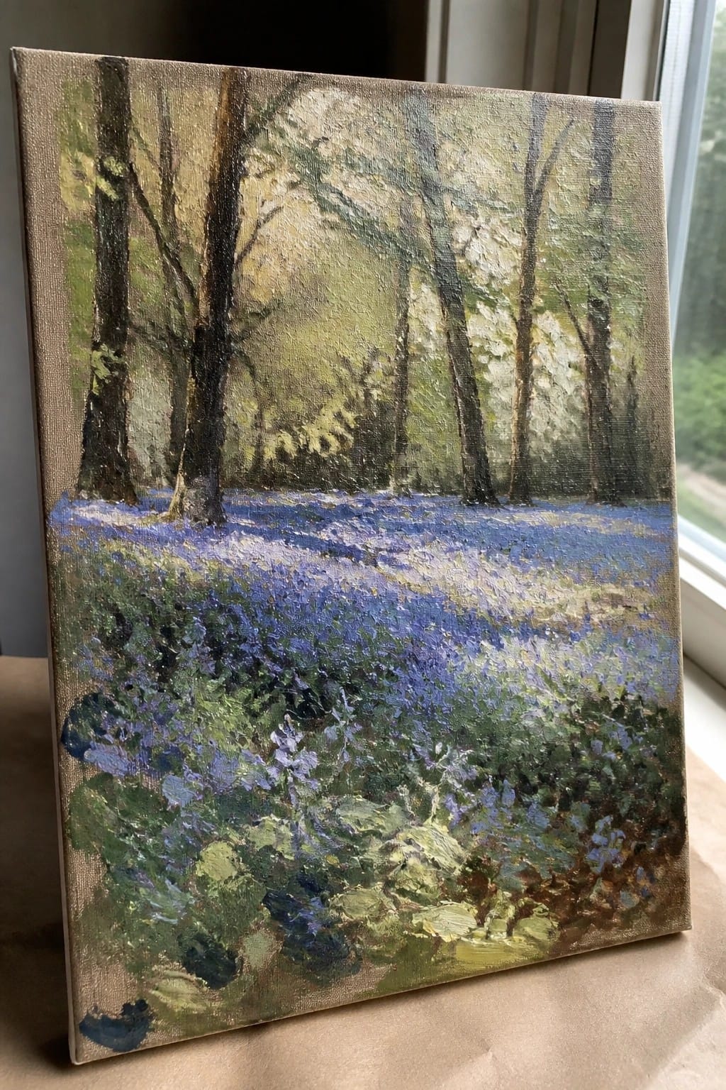 Impressionistic oil painting of bluebells carpeting a forest floor beneath tall trees.