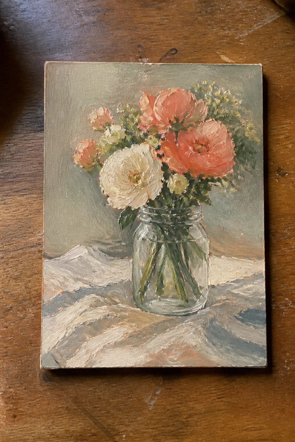 Oil painting of coral and white flowers in glass jar on white cloth