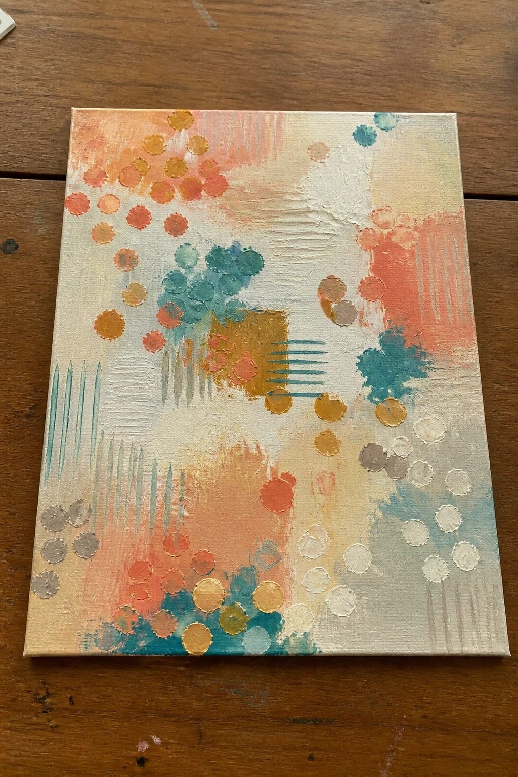 Abstract painting with colorful dots, brushstrokes, and shapes in orange and teal on canvas.