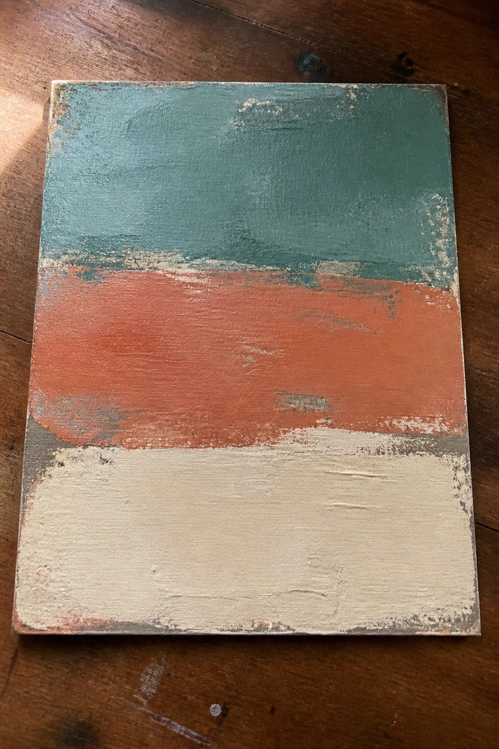 Abstract painting with horizontal bands of teal, orange, and off-white on wood