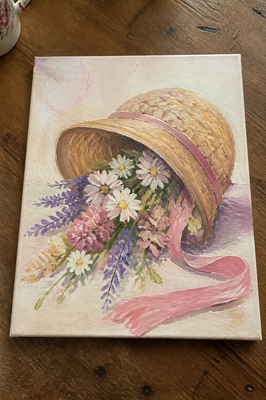 Straw hat with pink ribbon overflowing with daisies, lavender, and wildflowers