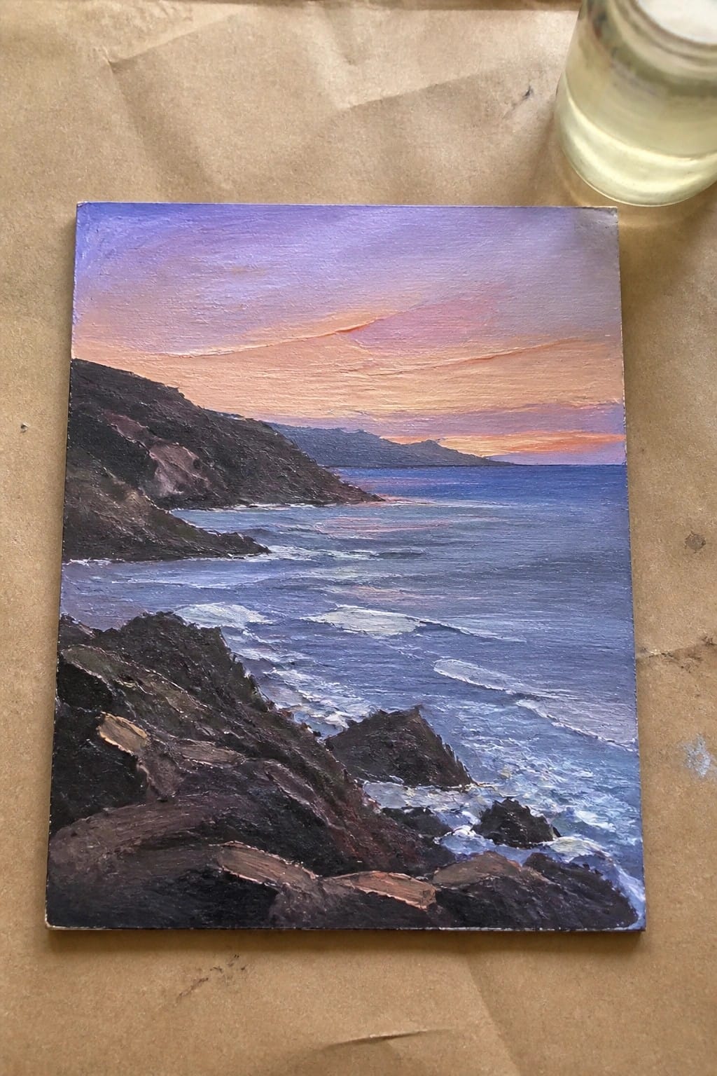 Oil painting of waves crashing on rocky cliffs under purple-orange sunset sky.