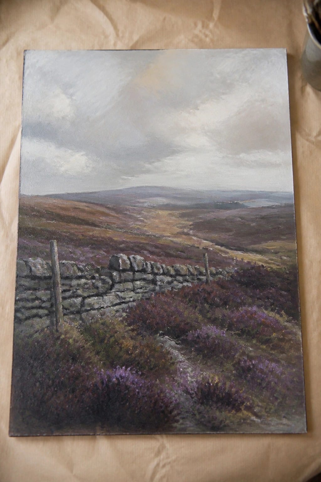 Oil painting of purple heather moorland with foreground stone wall under cloudy sky.