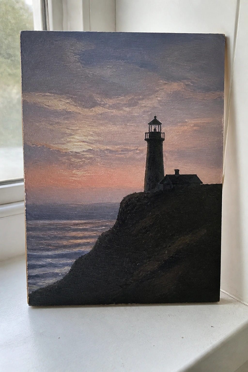 Silhouetted lighthouse on rocky cliff overlooking ocean under vibrant sunset sky