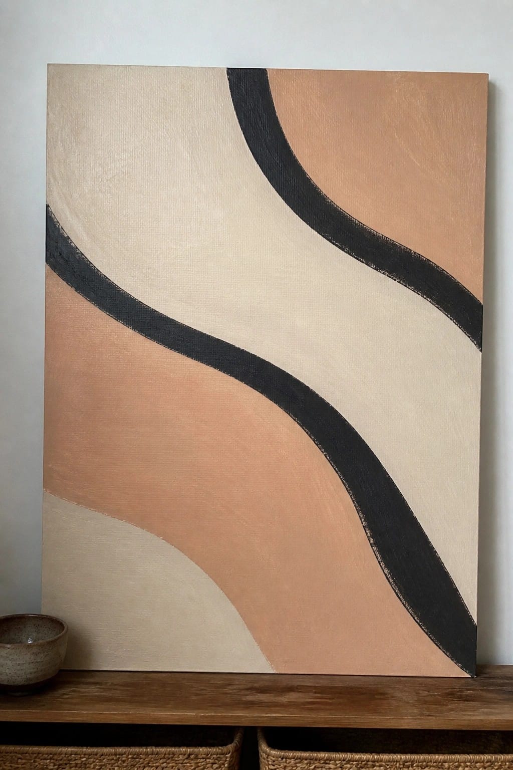Abstract painting with black wavy lines in beige and peach tones on wooden shelf
