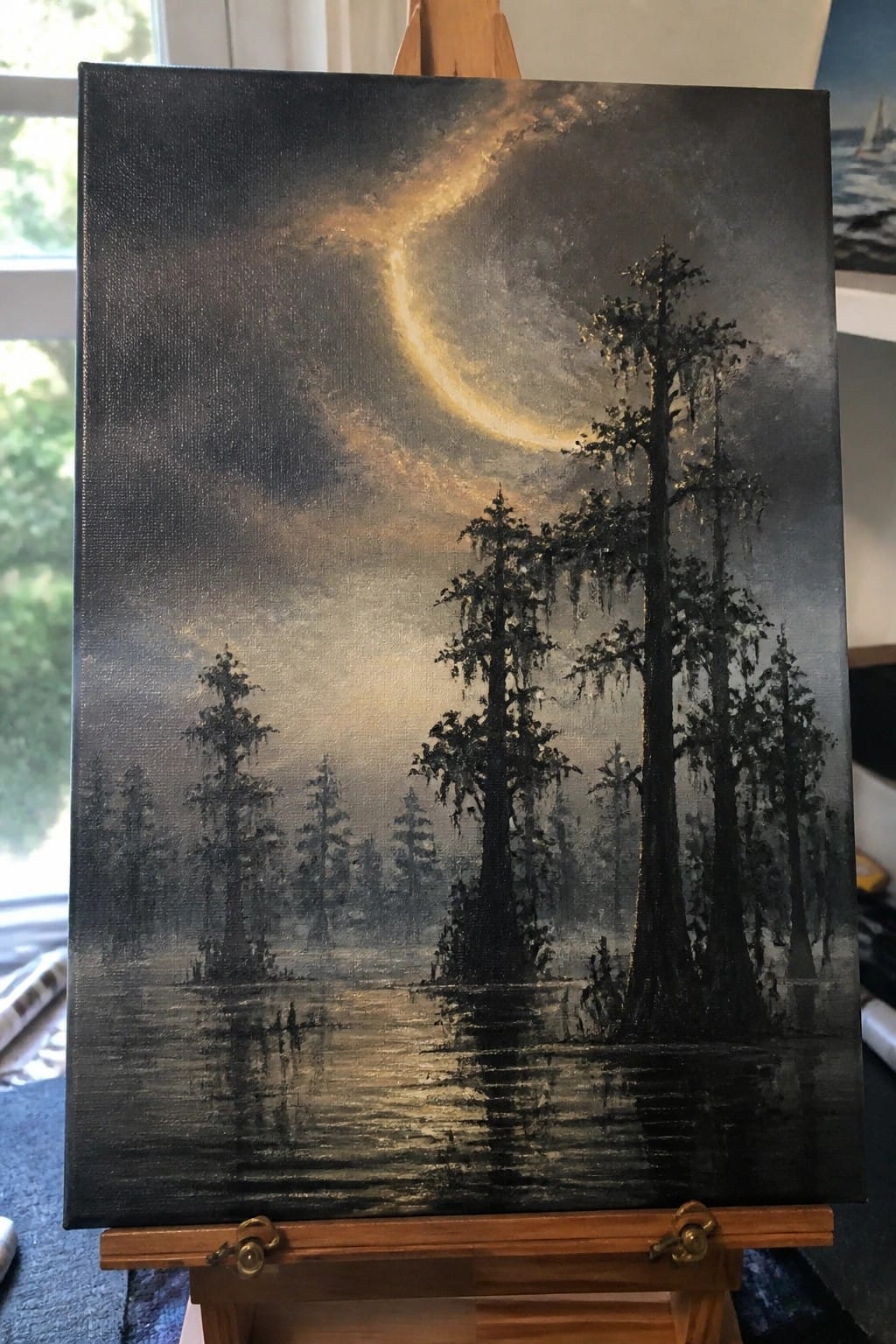 Painting of misty swamp with tall dark trees under glowing golden sky on easel