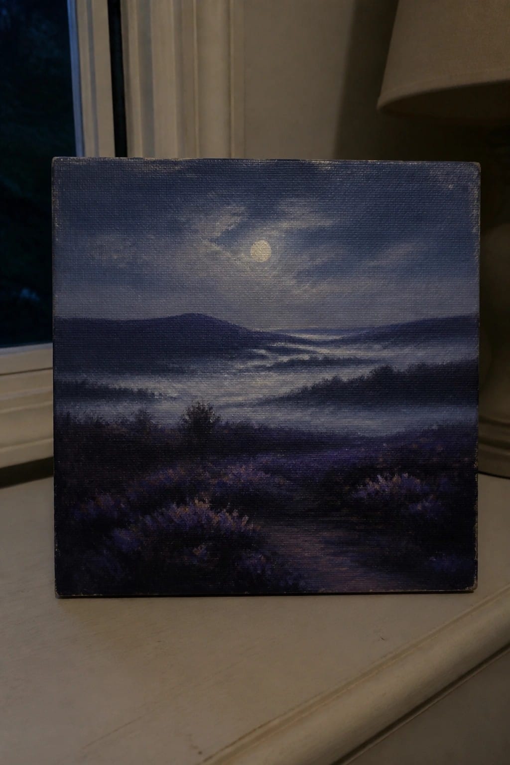 Small canvas painting of moonlit misty mountains with purple foliage on a ledge.