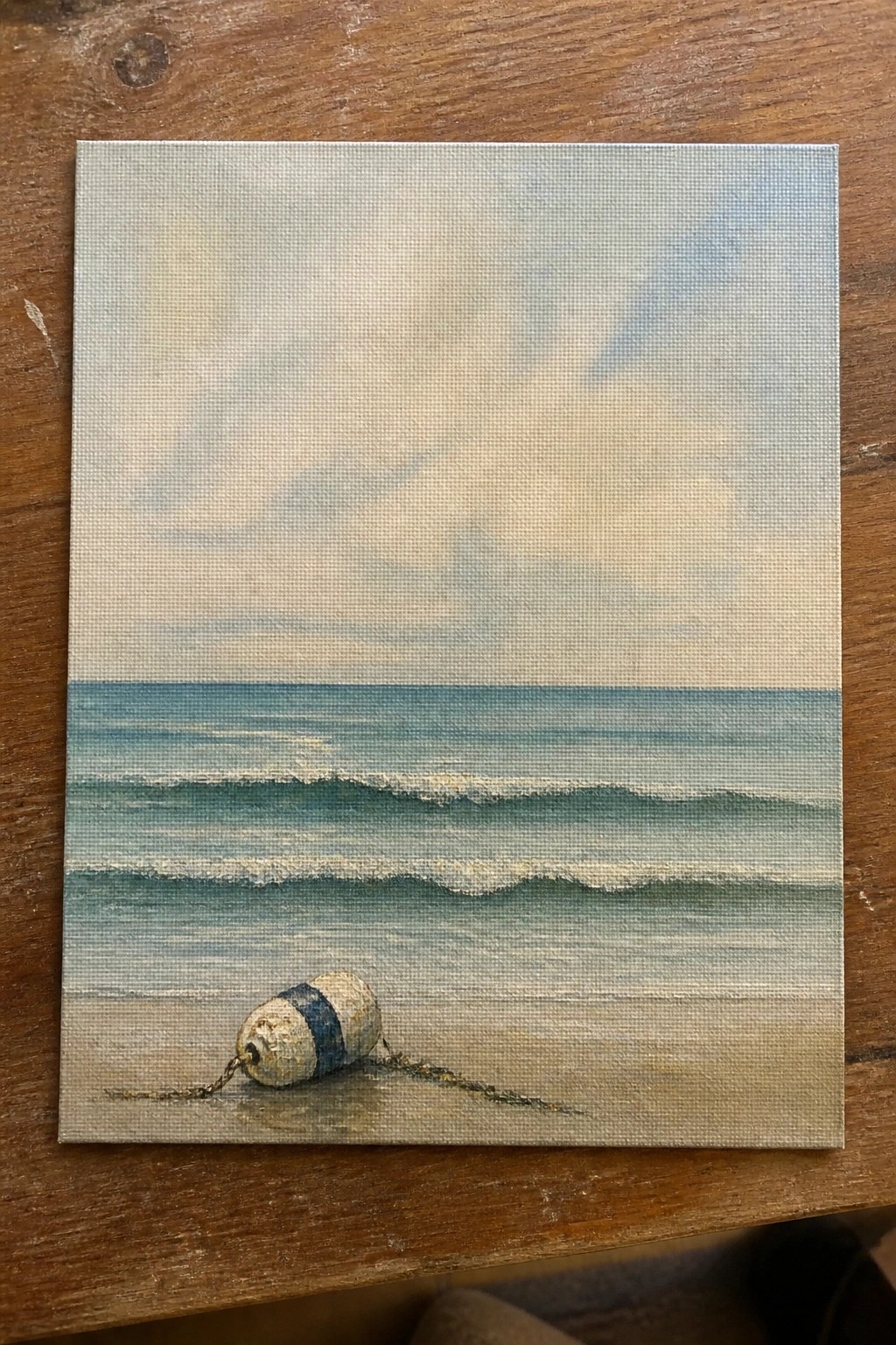 Miniature seascape painting of striped buoy with chain on sandy beach by ocean waves under clouds
