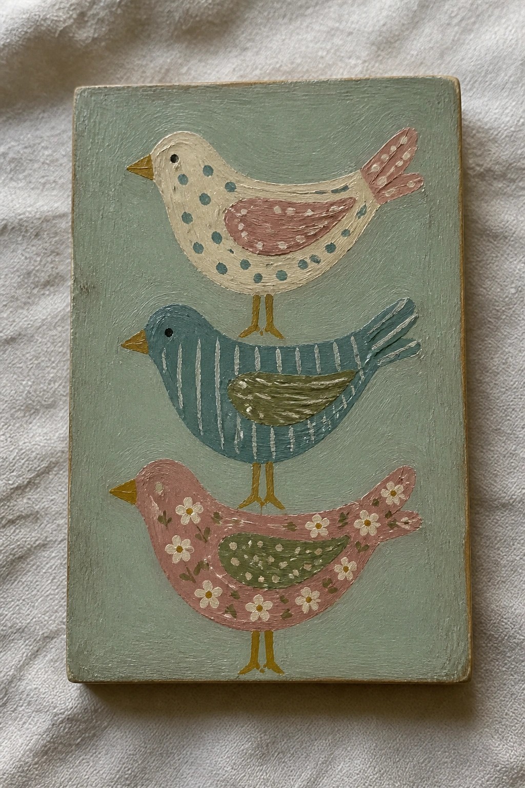 Three stacked stylized birds in pastel patterns on light green canvas.