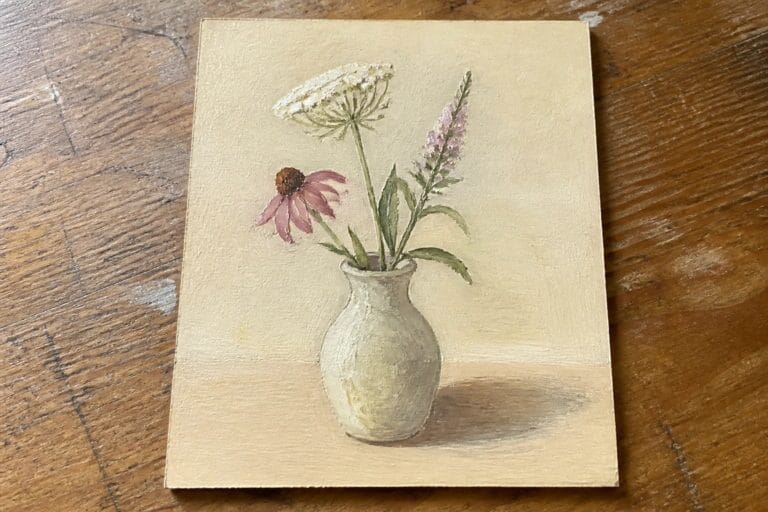 Small white vase with pink and white flowers casting shadow on wood