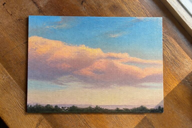 19 Simple Oil Painting Ideas Using Nature, Sky, and Water as Canvas Inspiration Small canvas painting of sunset sky with orange-pink clouds above green horizon on wood.