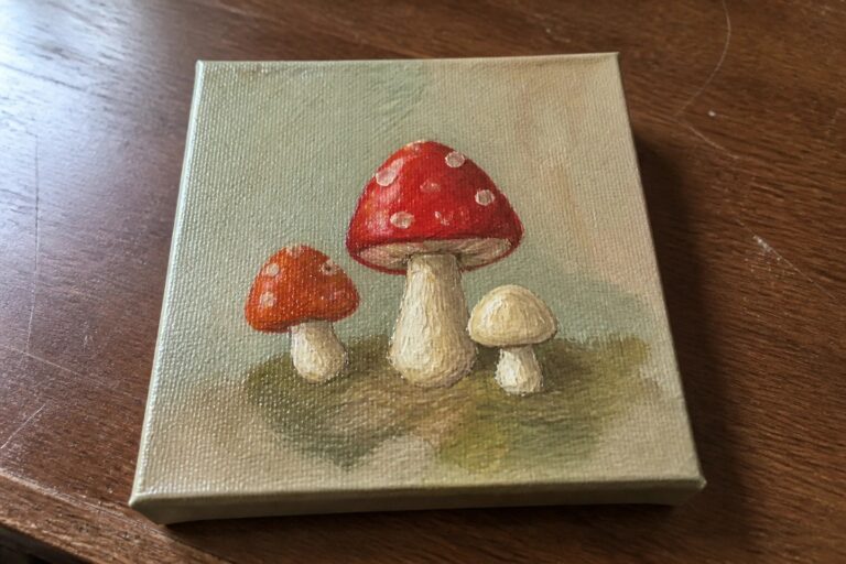 19 Unique Mini Canvas Oil Painting Ideas for Small Creative Sessions Small canvas painting of three mushrooms: red spotted, brown, and beige on green.