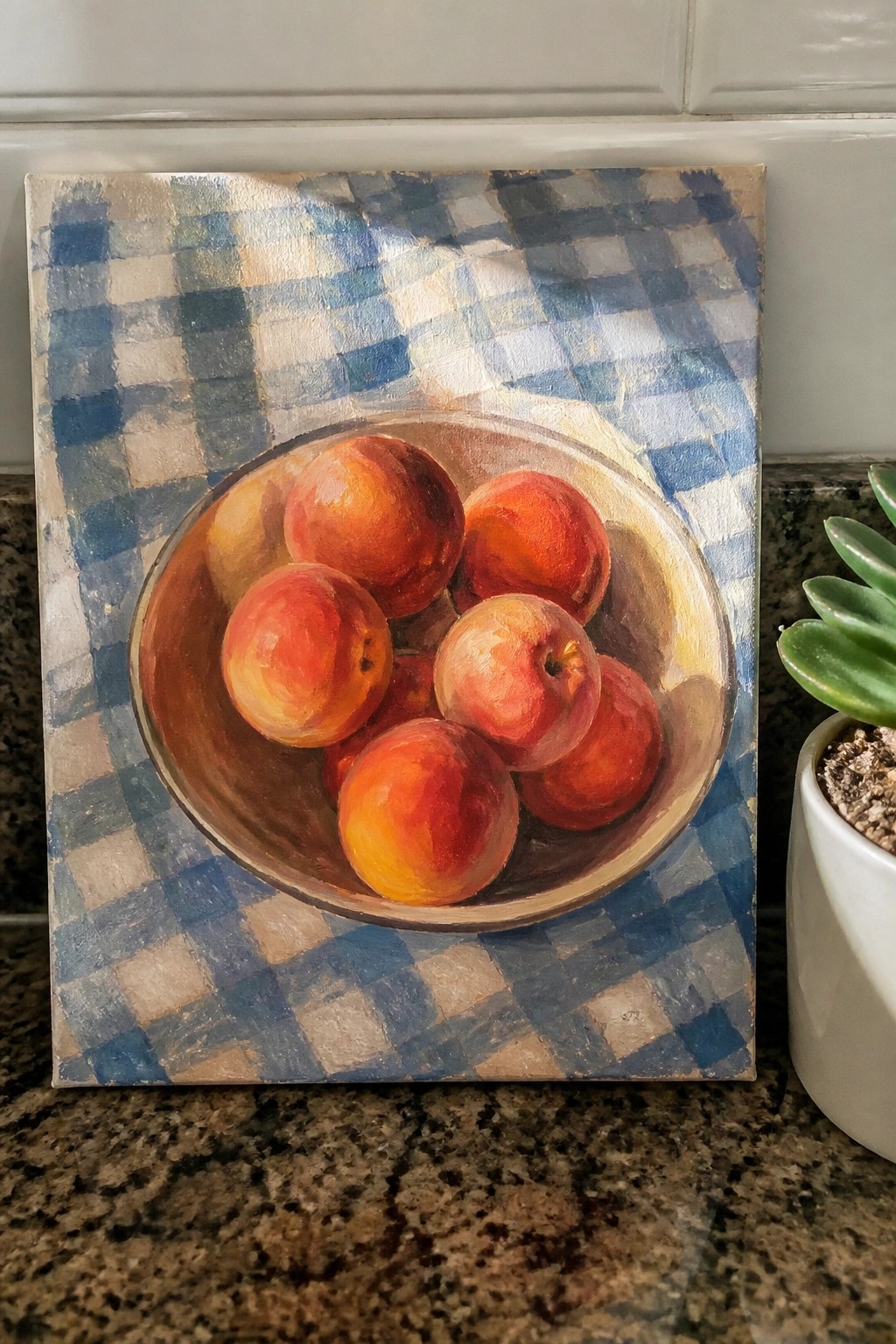 Still life painting of peaches in bowl on blue checkered cloth beside succulent plant