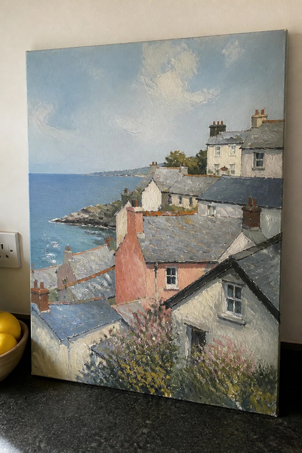 Coastal village painting with colorful rooftops, red chimney, and blue sea beyond
