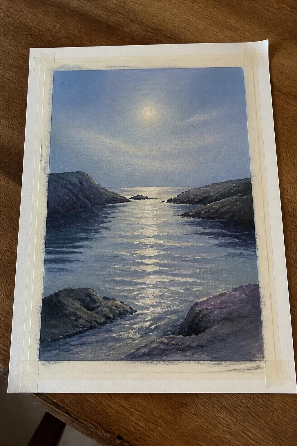 Moonlit seascape painting with full moon reflecting on water between rocky cliffs.