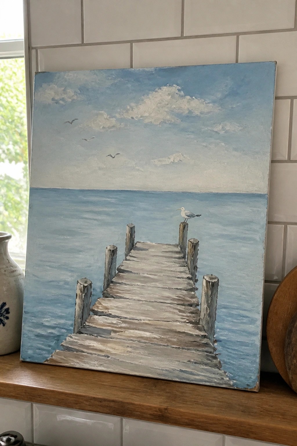 Painting of wooden pier over blue sea with seagull on post, birds in cloudy sky