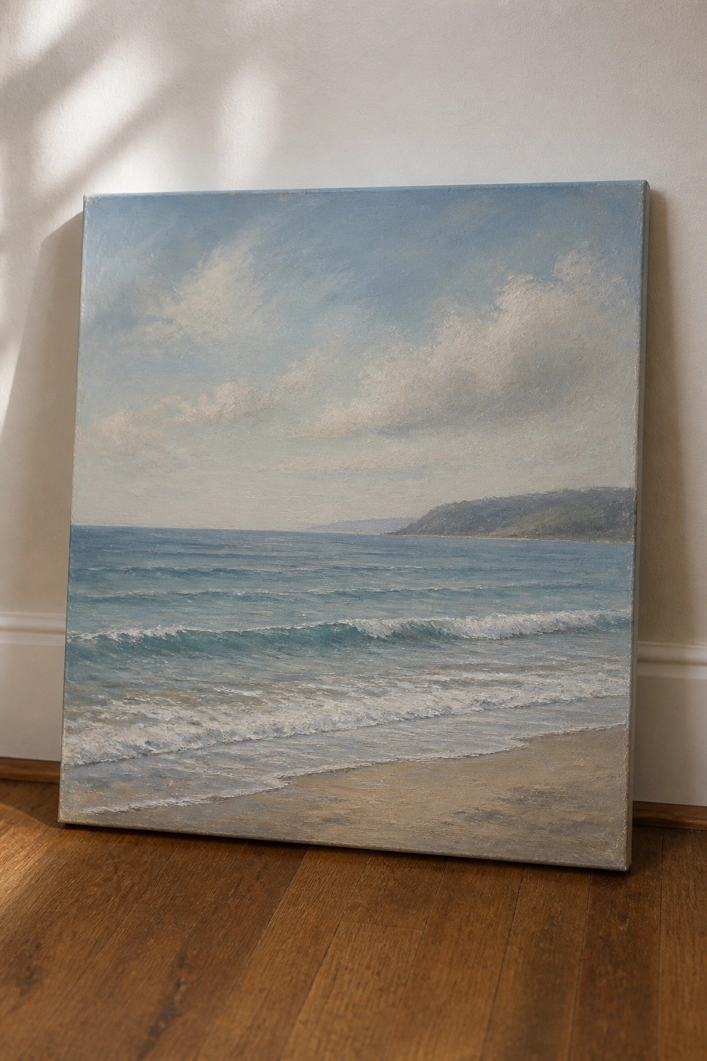 Seascape painting of ocean waves on sandy beach leaning against wall on wood floor