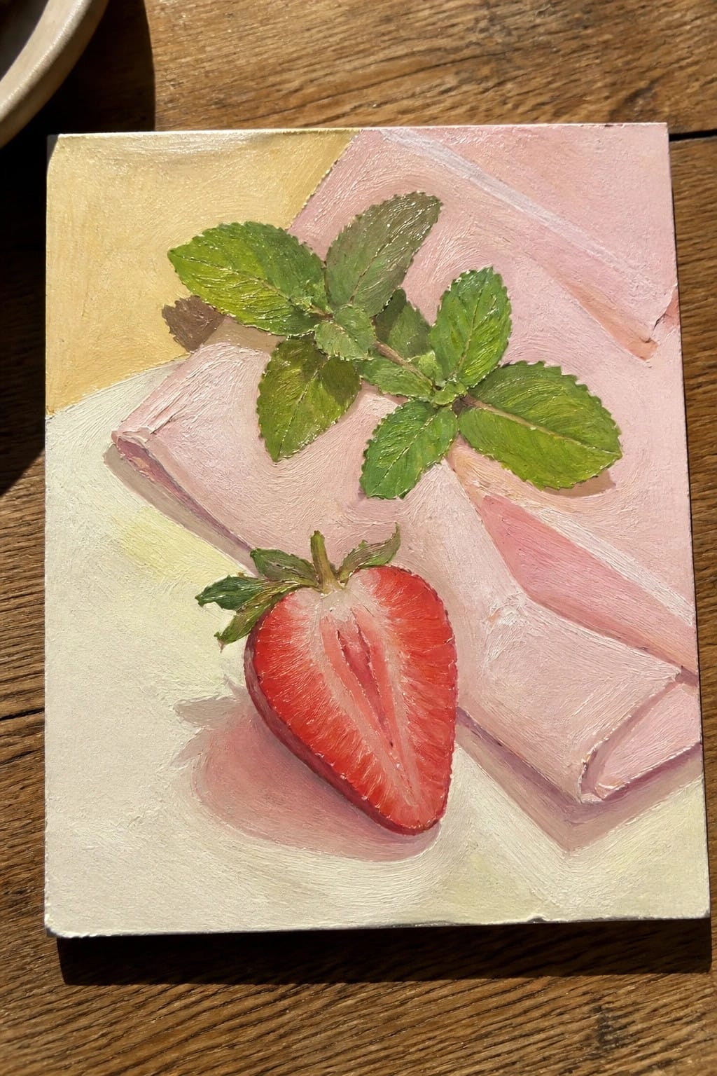 Painting of halved strawberry and mint leaves on pink-yellow abstract background