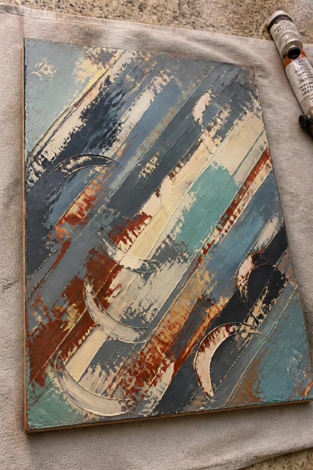 Abstract canvas with diagonal blue teal rust stripes and raised crescent shapes.