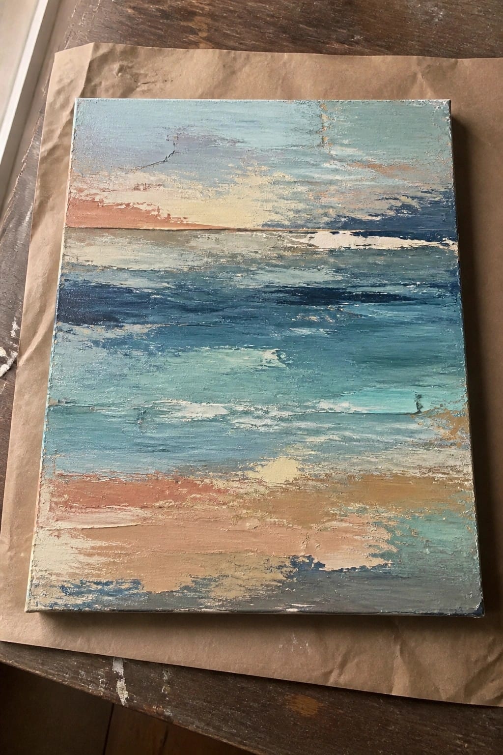 Abstract seascape painting with blue teal waves and orange tones on brown paper.