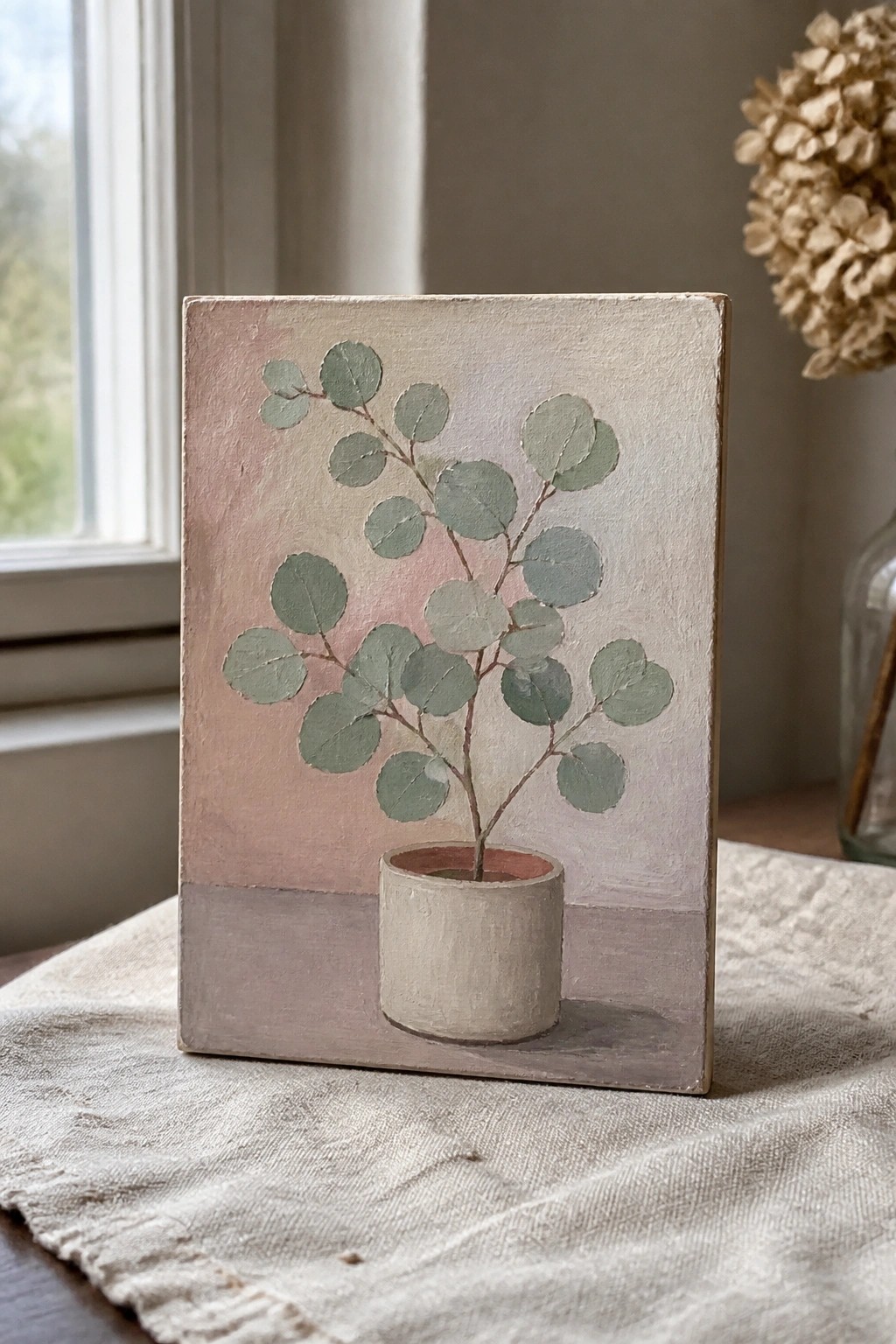 Painting of potted plant with round green leaves on soft pink background