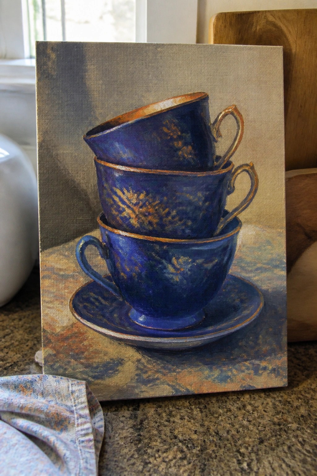 An oil painting of three stacked blue teacups with gold rims on a saucer, set against a textured neutral background.