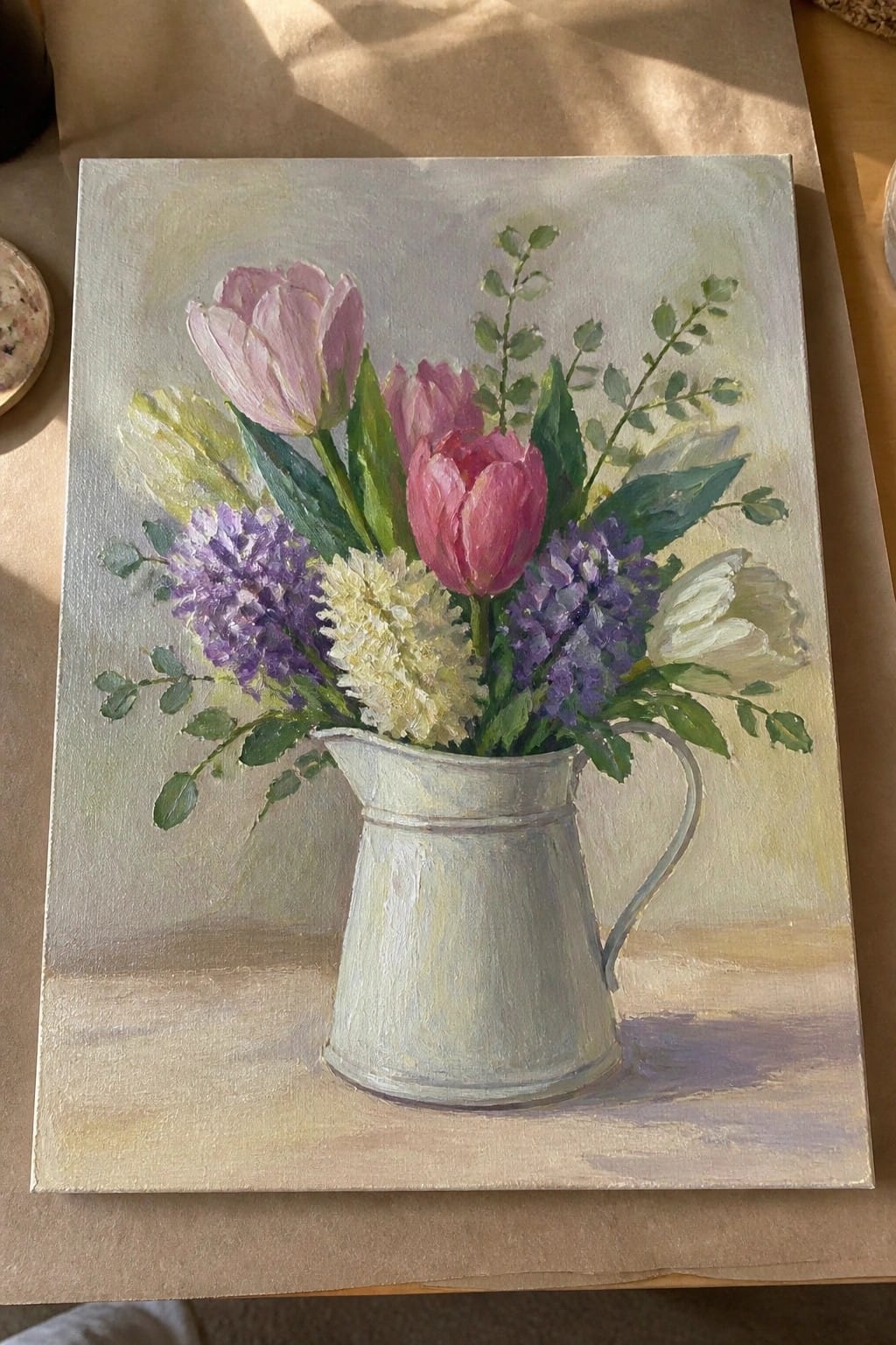 Pink purple tulips and flowers in a white metal pitcher on wood