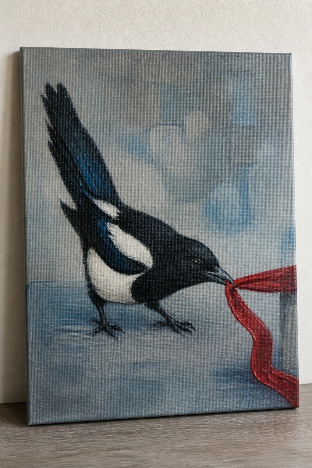 Black and white magpie with blue wings holds flowing red ribbon in beak