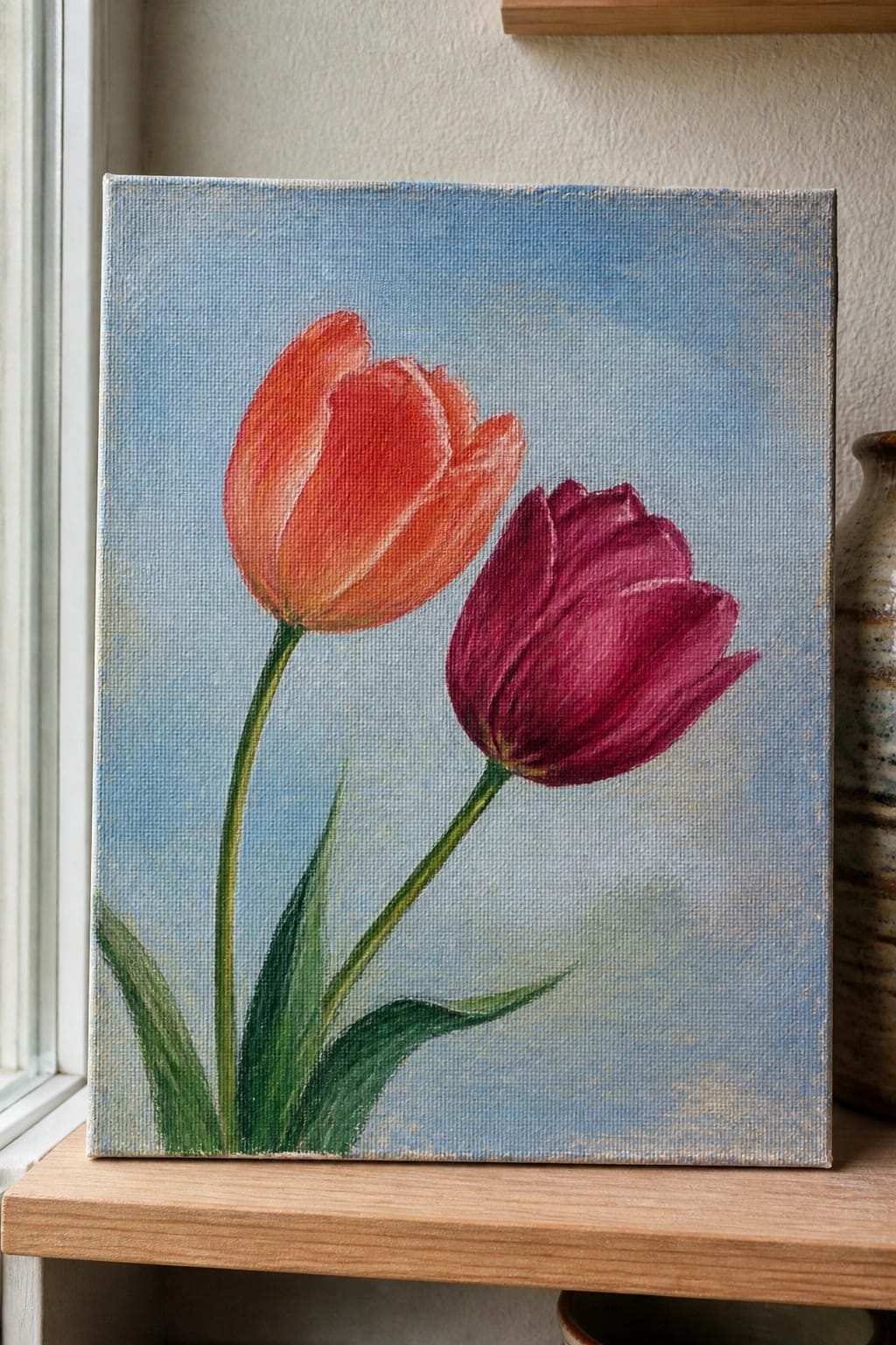 Painting of orange and purple tulips with green stems on blue canvas